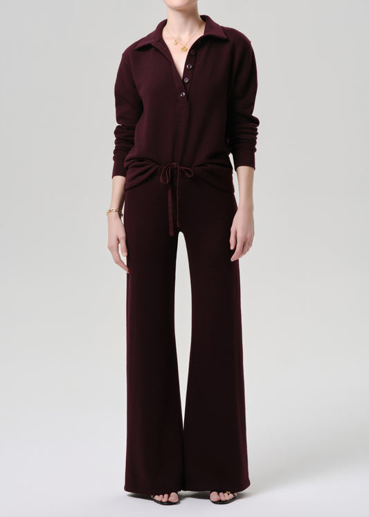 Person wearing a maroon jumpsuit on a grey background