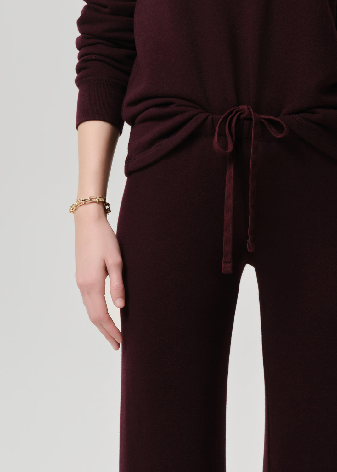 Burgundy outfit with a tied waist on a grey background
