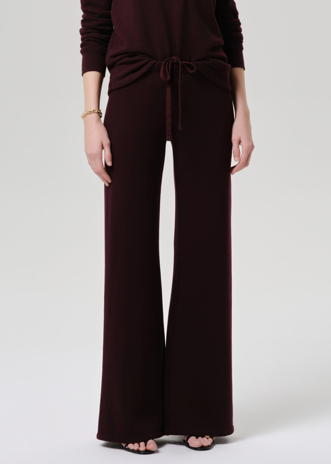 Person wearing a dark brown jumpsuit on a grey background