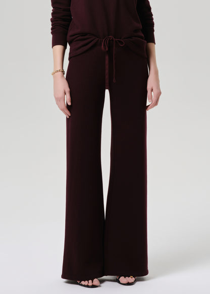 Person wearing a dark brown jumpsuit on a grey background