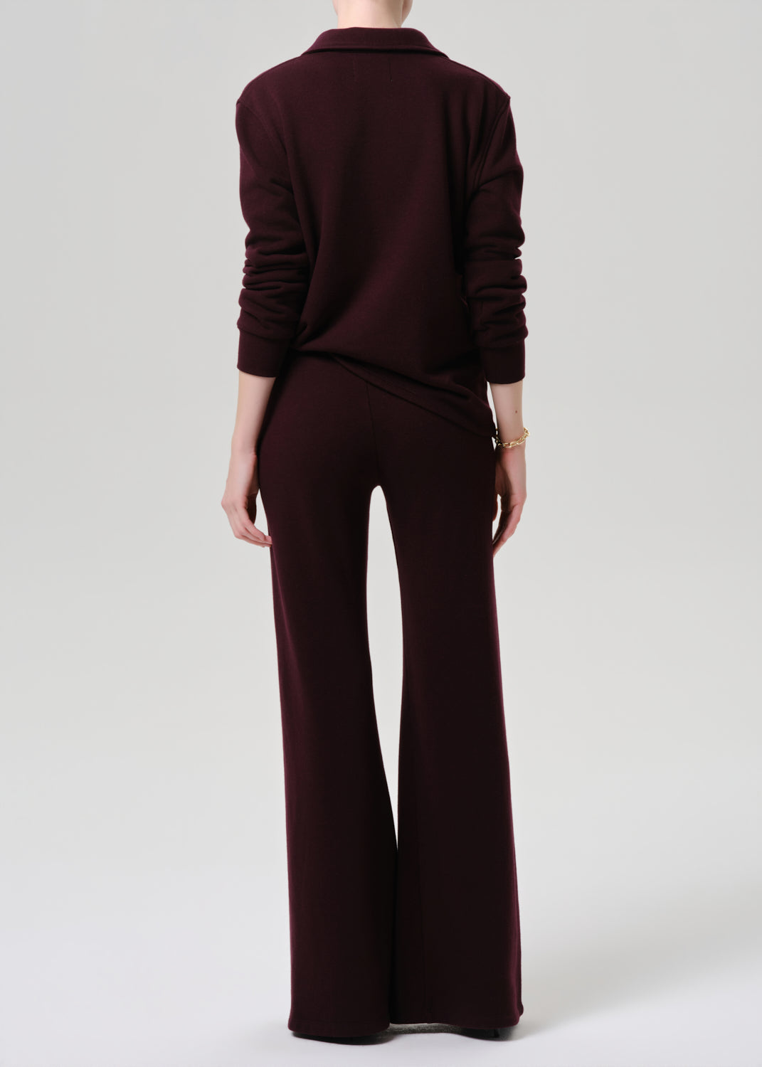 Person wearing a dark brown outfit with wide-leg pants on a grey background