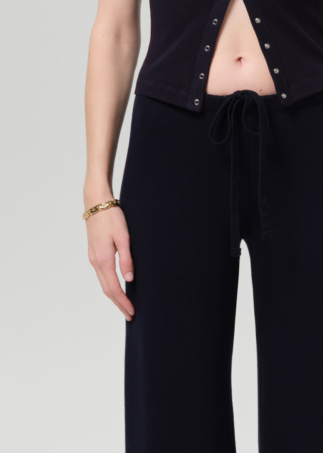 Person wearing a navy outfit with a buttoned top and wide-leg pants on a plain background