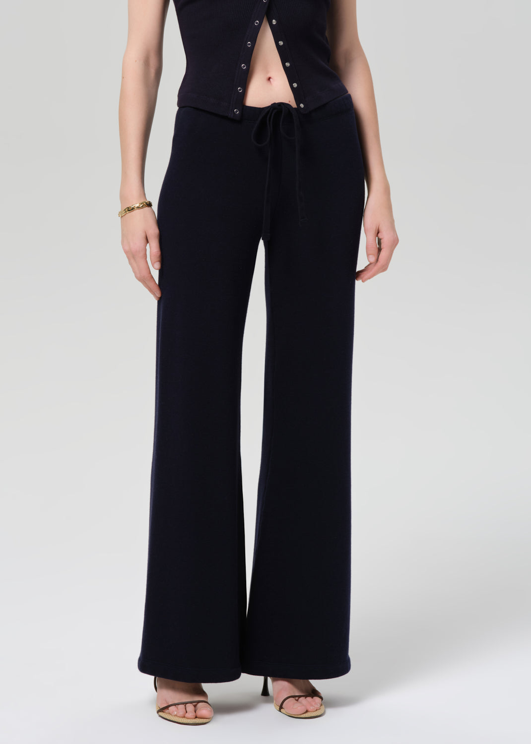 Person wearing a navy outfit with a buttoned top and wide-leg pants on a plain background