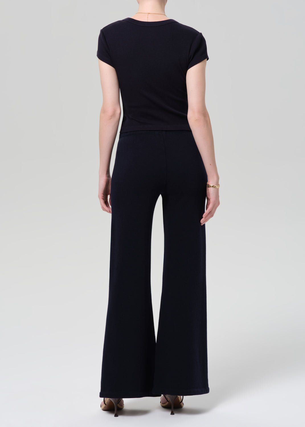 Person wearing a navy outfit with a buttoned top and wide-leg pants on a plain background