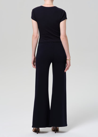 Person wearing a navy outfit with a buttoned top and wide-leg pants on a plain background