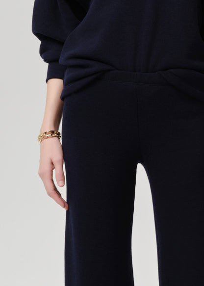 Person wearing a navy outfit with a grey background.