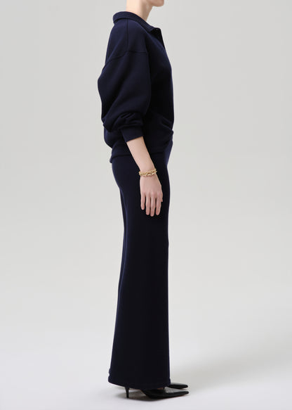 Person wearing a navy blue outfit on a grey background.