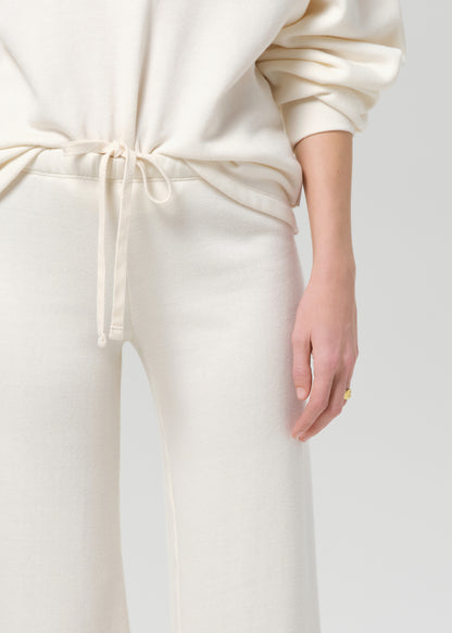 Person wearing a cream-colored sweatshirt and pants on a plain background