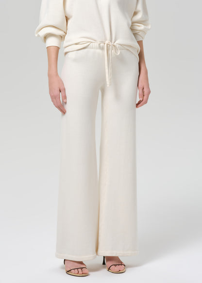 Person wearing a cream-colored sweatshirt and pants on a plain background