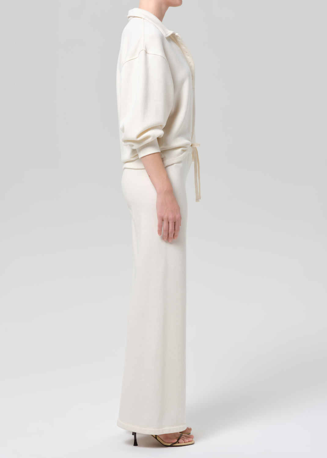 Person wearing a cream-colored sweatshirt and pants on a plain background