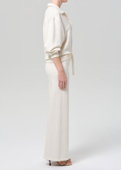 Person wearing a cream-colored sweatshirt and pants on a plain background