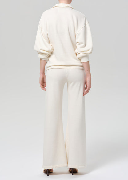 Person wearing a cream-colored sweatshirt and pants on a plain background