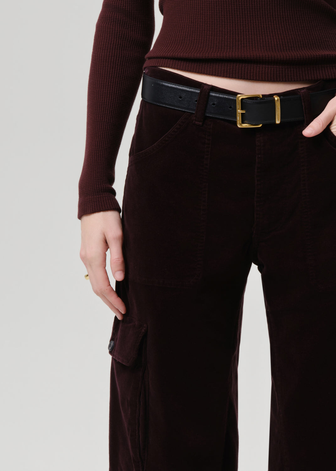 Person wearing a maroon sweater and dark brown cargo pants with a black belt.