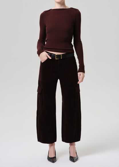 Person wearing a burgundy long-sleeve top and dark brown wide-leg pants on a grey background
