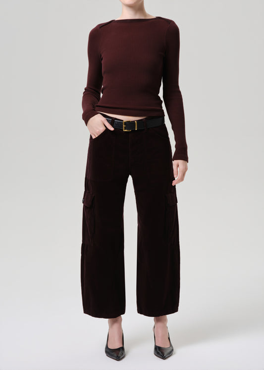 Person wearing a burgundy long-sleeve top and dark brown wide-leg pants on a grey background