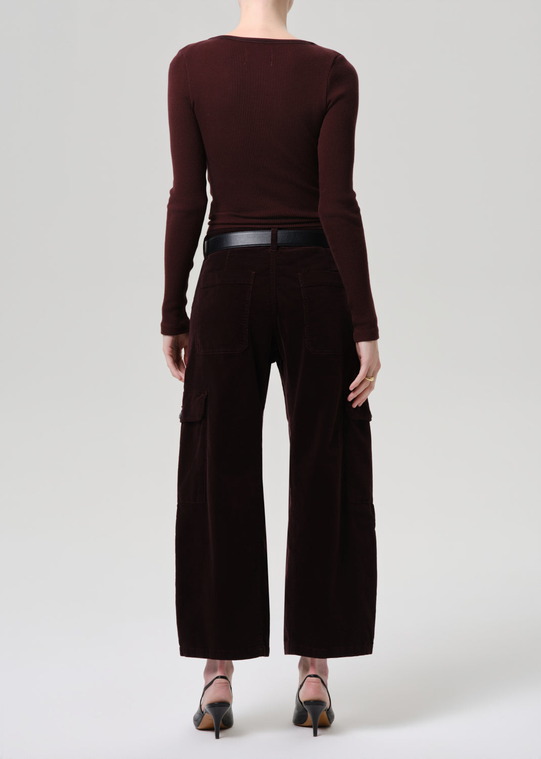 Person wearing a brown long-sleeve top and wide-leg pants on a grey background