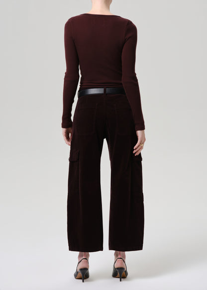 Person wearing a brown long-sleeve top and wide-leg pants on a grey background