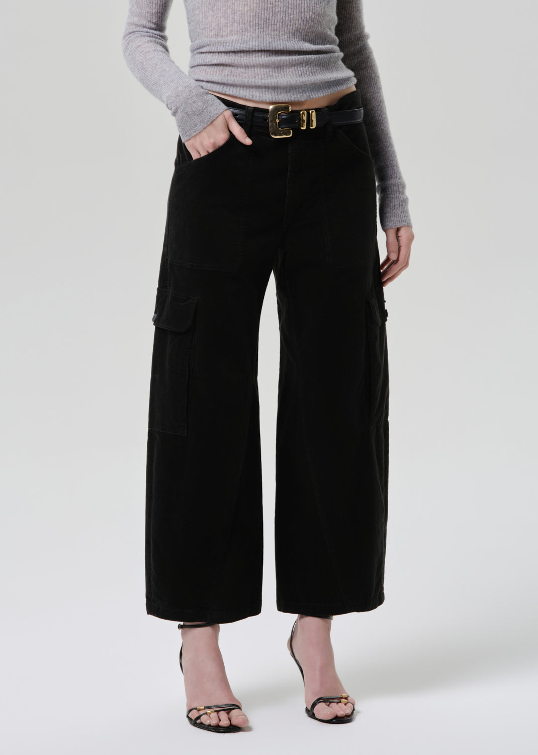Person wearing black wide-leg pants and a grey sweater on a white background