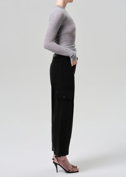 Person wearing a grey sweater and dark green pants on a grey background