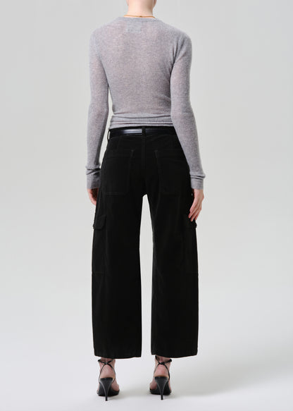 Person wearing a grey long-sleeve top and dark green wide-leg pants on a grey background