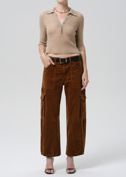 Person wearing a beige sweater and brown cargo pants on a grey background