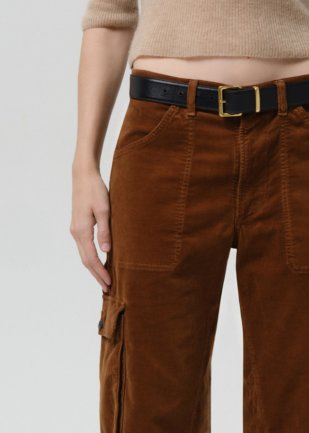 Brown cargo pants with a black belt on a grey background