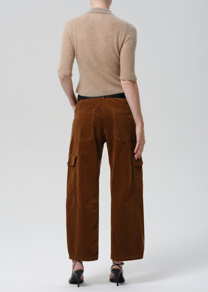 Person wearing a beige sweater and brown cargo pants on a grey background