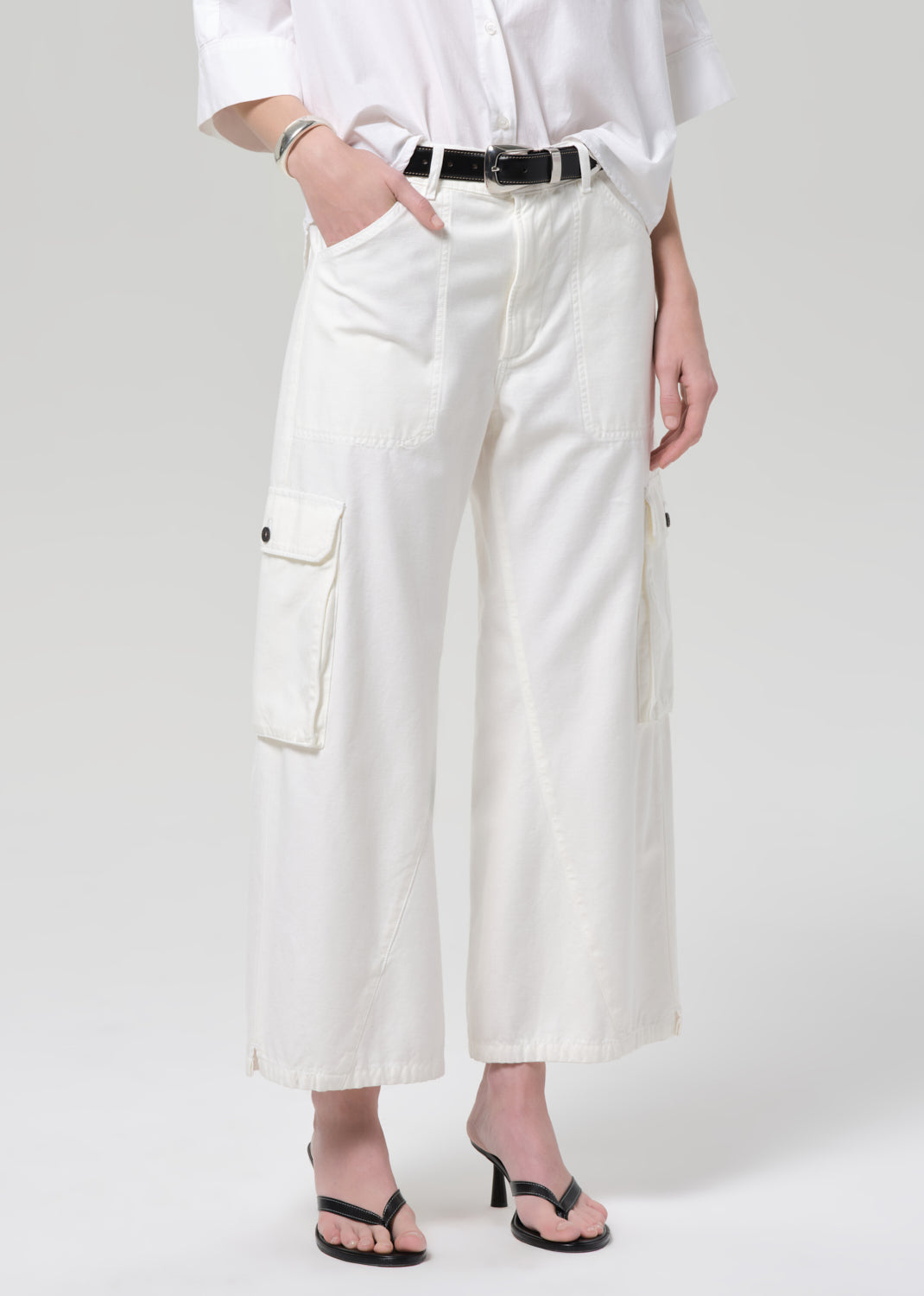 Person wearing a white outfit with wide-leg pants on a plain background