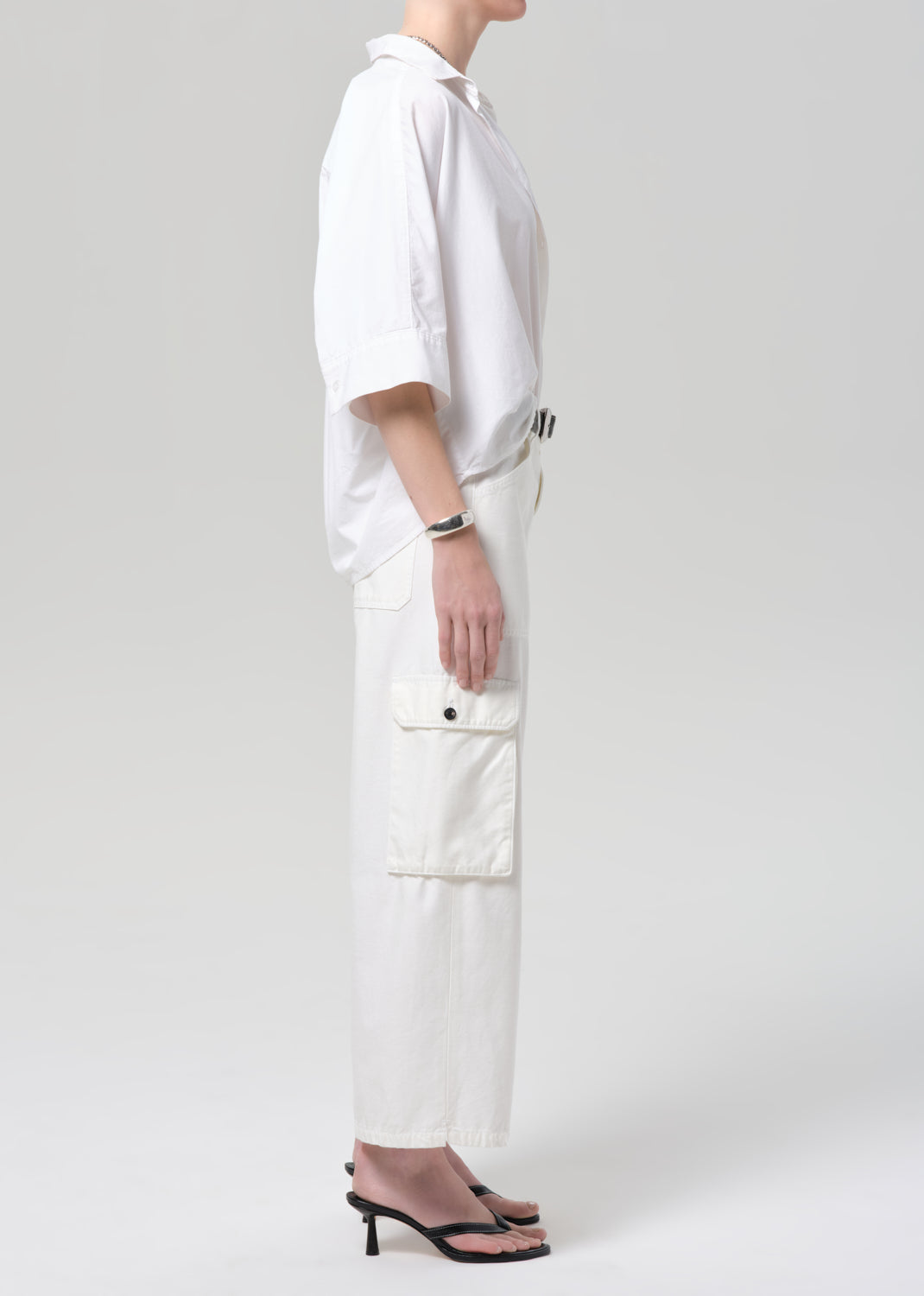Person wearing a white outfit with cargo pants on a plain background