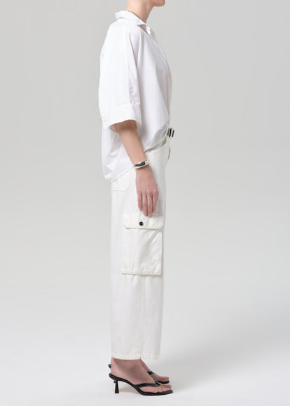 Person wearing a white outfit with cargo pants on a plain background