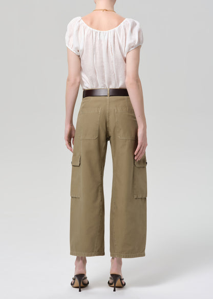 Person wearing a white top and green cargo pants on a plain background
