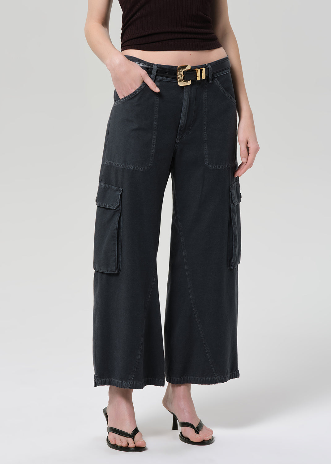 Person wearing a brown halter top and wide-leg cargo pants on a plain background