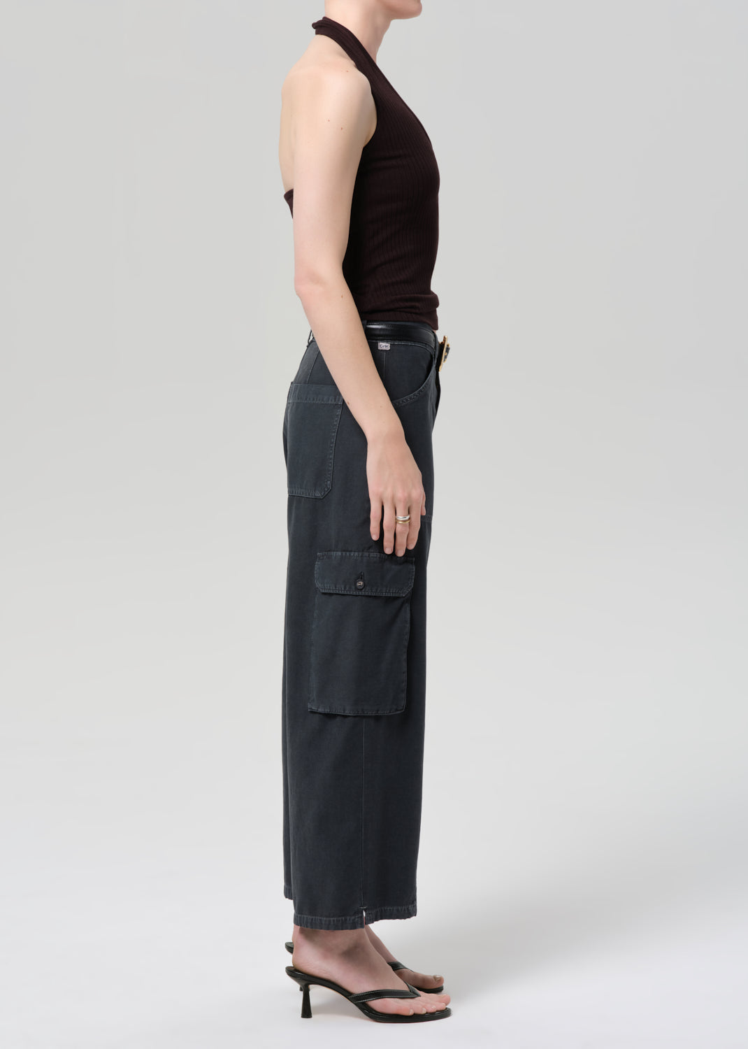 Person wearing a brown halter top and wide-leg cargo pants on a plain background