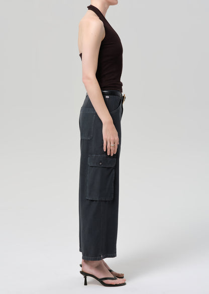 Person wearing a brown halter top and wide-leg cargo pants on a plain background
