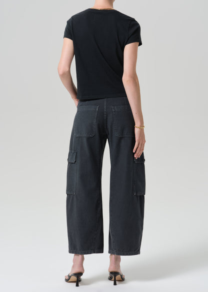 A model shown from the back wearing a black short-sleeve t-shirt and dark charcoal gray wide-leg cargo pants, paired with black heeled sandals, against a grey background.
