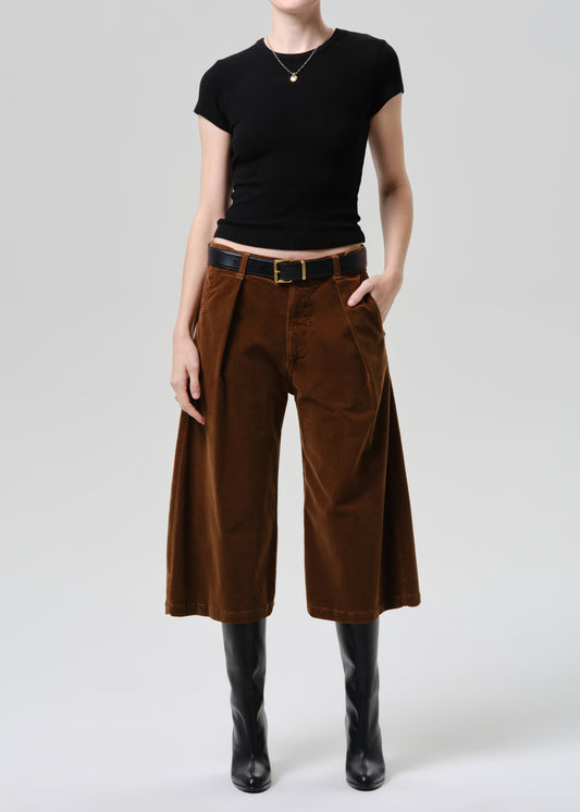 Person wearing a black top and brown wide-leg pants on a grey background