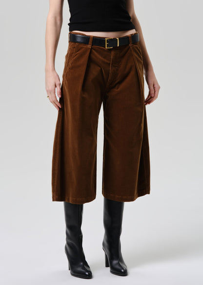 Person wearing brown wide-leg pants and black boots on a grey background