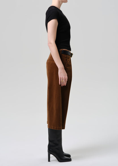 Person wearing brown pants and black boots on a grey background