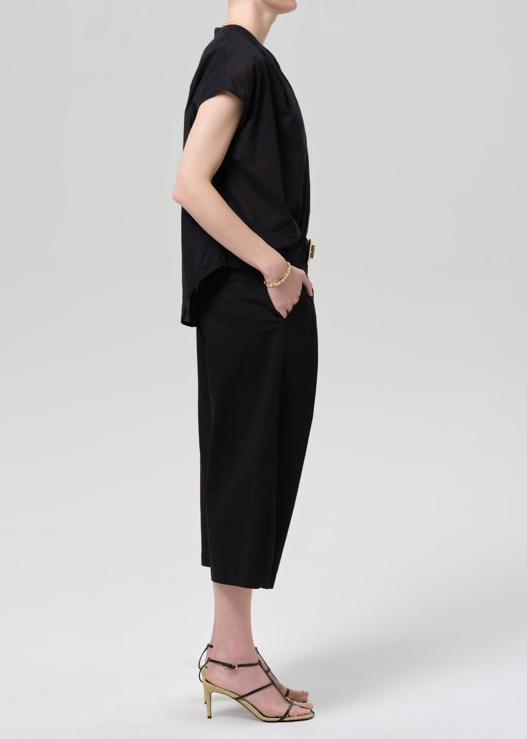 Person wearing a black outfit with wide-leg pants on a grey background