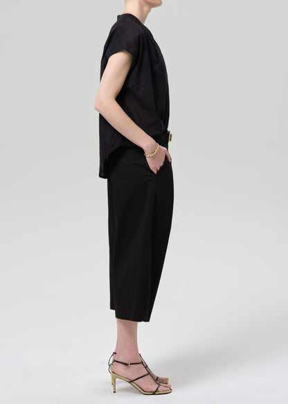 Person wearing a black outfit with wide-leg pants on a grey background