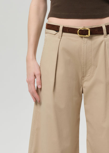 Person wearing a brown sleeveless top and beige wide-leg pants on a grey background