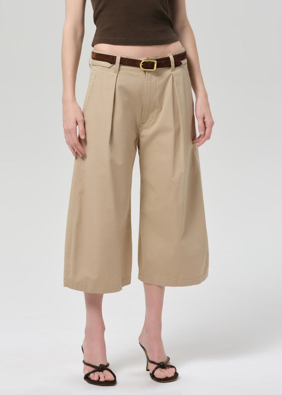 Person wearing a brown sleeveless top and beige wide-leg pants on a grey background