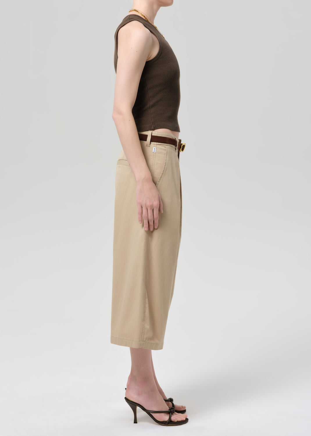Person wearing a brown sleeveless top and beige wide-leg pants on a grey background