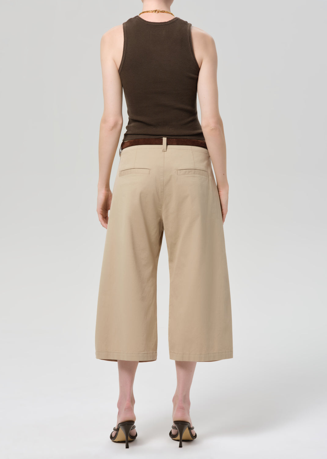 Person wearing a brown sleeveless top and beige wide-leg pants on a grey background