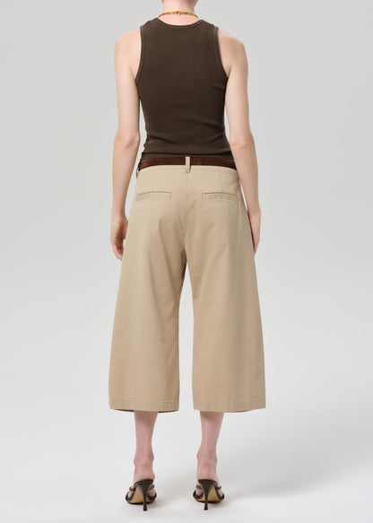 Person wearing a brown sleeveless top and beige wide-leg pants on a grey background