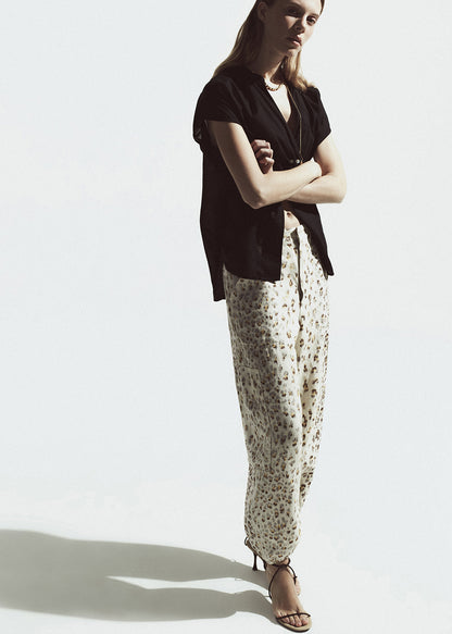 Woman wearing a black top and  leopard pants on a white background