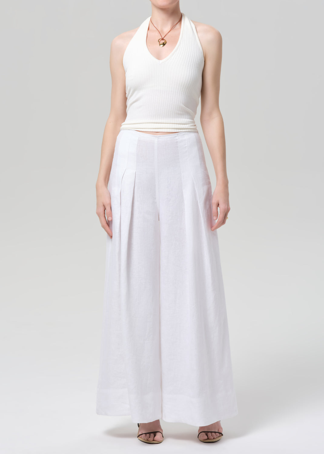Woman wearing a white halter top and palazzo pants on a light gray background