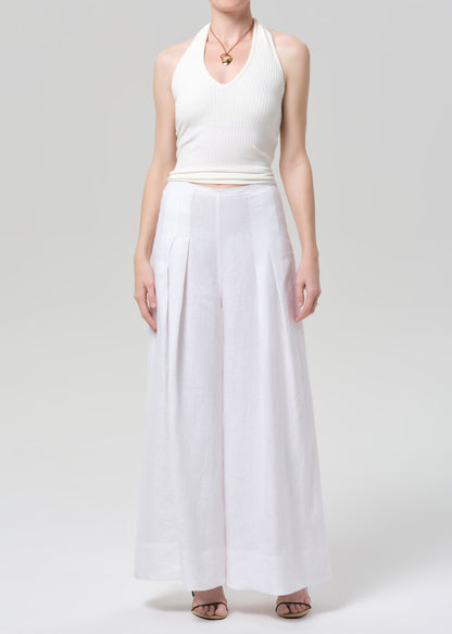 Woman wearing a white halter top and palazzo pants on a light gray background