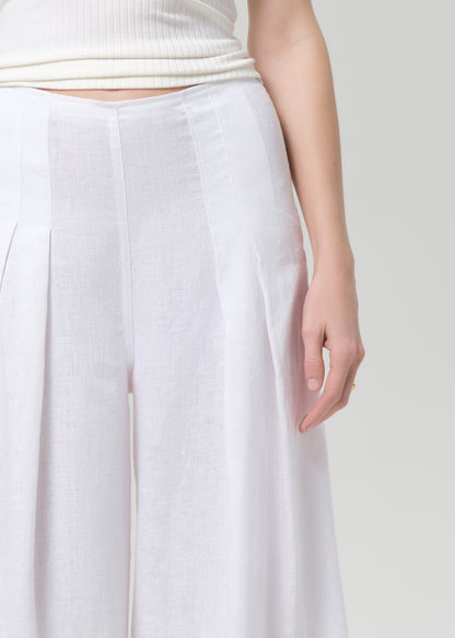 Woman wearing a white halter top and palazzo pants on a light gray background
