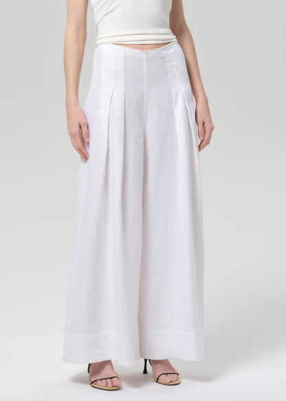 Woman wearing a white halter top and palazzo pants on a light gray background